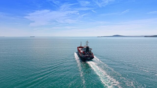 Following a large ship moving by the beautiful waterscape. Vessel heading to the ships standing on the roadstead.