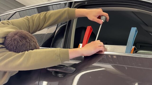PDR. The mechanic at the auto shop with tools to repair dents in car body. Body repair. A specialist repairs a dent on the car body without painting. Paintless Car Dent Repair. 