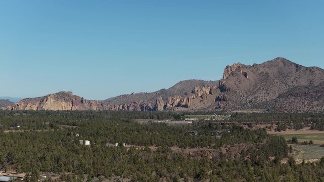 Aerial of rural homes in juniper trees in Redmond Oregon high desert in spring with view of Smith Rock State Park