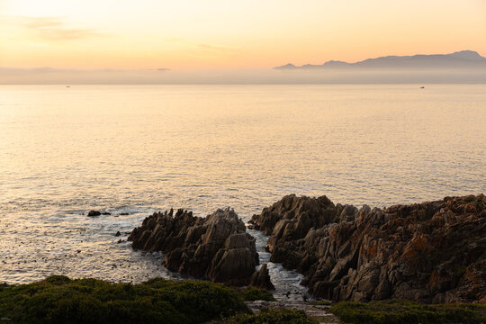 2 pre teen boys climbing and exploring the rocky coastline of DeKelders, South Africa