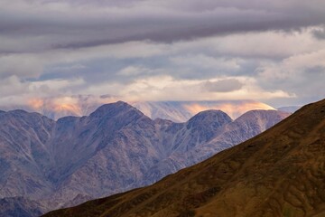 Fototapeta premium Play of light over Himalayan mountains of Stok Village, Leh, Ladakh, India. Known for Stok Palace, heritage hotel and Stok Monastery. Base of Stok Kangri peak in Hemis National Park, mountainscape.