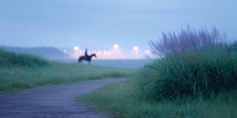 Fototapeta premium a person riding a horse in the distance, with street lights and fields in the background at dusk