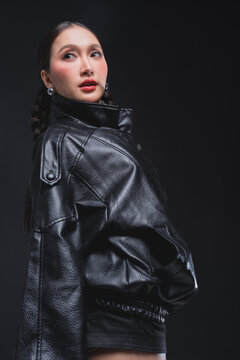 Side profile of Asian woman looking over shoulder in leather jacket for high fashion cosmetics marketing campaign luxury streetwear aesthetic urban lifestyle edgy portrait studio
