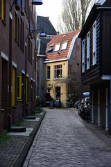 Fototapeta premium Charming narrow historic city street leading towards a quaint yellow house with a tiled roof