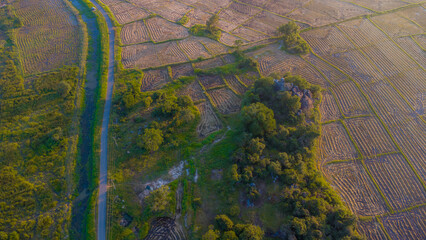 Bird's-eye view of a countryside village featuring lush grasslands and cultivated paddy fields. © Roshan Harshana