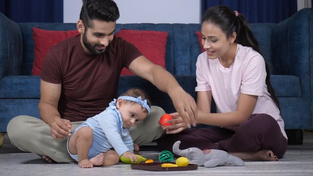 A young Indian couple playing with their little daughter at home - parenting  young parents  happy parents  modern parents . A cute baby girl playing with her toys while sitting comfortably on the ...