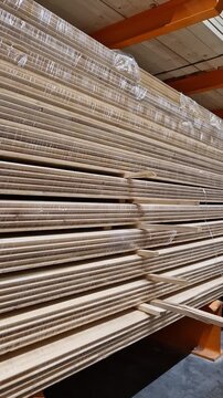 Wooden lining made of softwood in bundles. A stack of wooden panels (lining) made of natural softwood, packed in transparent film. Building materials for finishing walls and ceilings in a warehouse