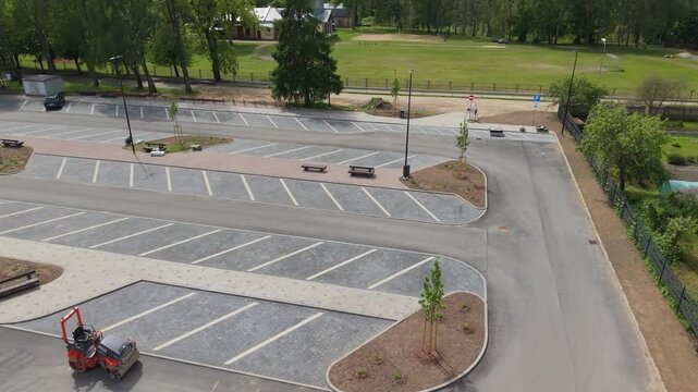Aerial view of a parking lot with landscaping, benches, and vehicles, showcasing the layout and design progression in a green environment
