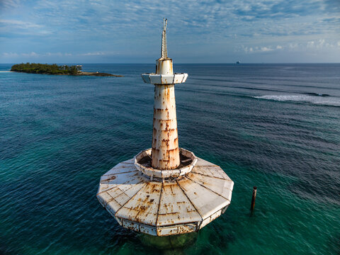 Aerial view of the rusty white beacon structure in the turquoise waters near Arawak Cay with a small island in the background Nassau, New Providence, The Bahamas.