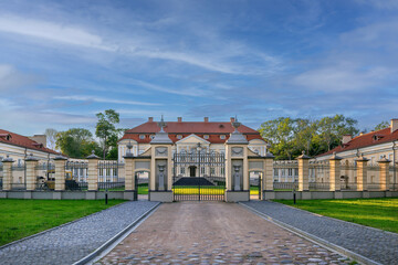 Fototapeta premium Volovich palace view through fence in Svyatsk, Belarus. Baroque and classicism architecture under bright clear blue sky