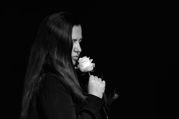 black and white profile portrait of a woman in dark clothing closely inhaling the fragrance of a rose © Родион Бондаренко