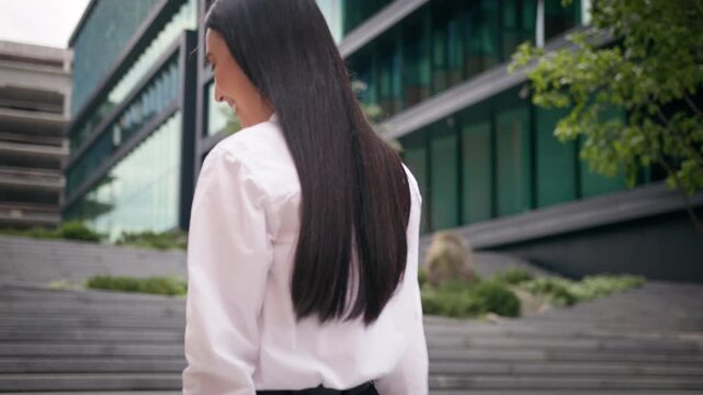 Back view Asian Korean business woman walking on stairs in city turning around smiling at camera happy Chinese Japanese stylish businesswoman smile walk in downtown girl manager female going to office