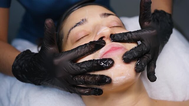 Cosmetologist applying cleansing foam for facial massage