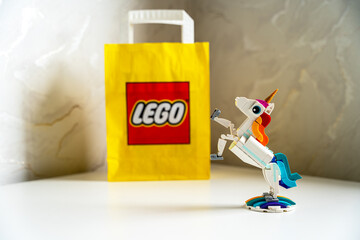 Obraz premium LEGO Creator 3-in-1 Magical Unicorn on white table with yellow LEGO paper bag. A built LEGO Creator Magical Unicorn toy figure stands in a rearing pose on a rainbow base.