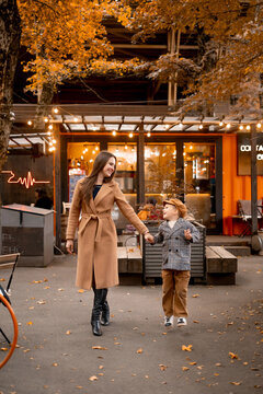 mother and child walking in the park in autumn, mother and little son walking together on a warm autumn day, hugging and laughing