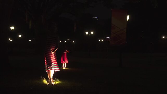 Sisters dance on spotlights in Bastejkalna park, Riga, capital of Latvia.