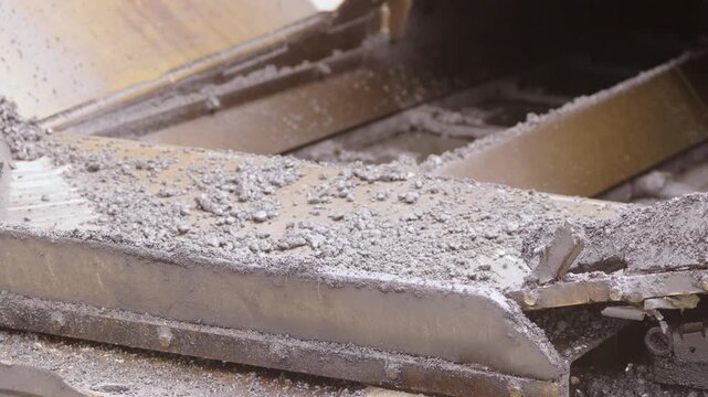 Close-up view of metallic surface with scattered debris and dust, showcasing gradual accumulation of particles in an industrial setting with visible machinery components