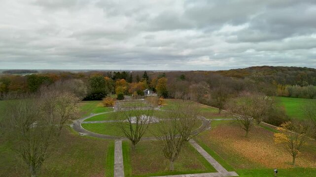 Aerial drone view of Hill 62 Canadian Memorial park in Ypres, Belgium. Historic World War I battlefield site and monument garden surrounded by autumn forest under clou