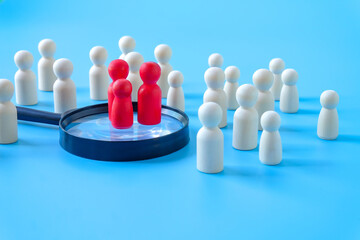 Obraz premium Wooden figures on magnifying glass,Recruitment employee concept.