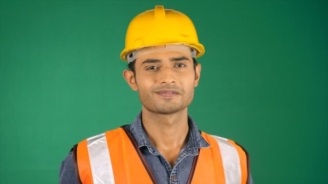 Confident-looking engineer standing while facing sideways against a green screen. A handsome Indian architect posing for the camera with a smile - construction worker  construction site