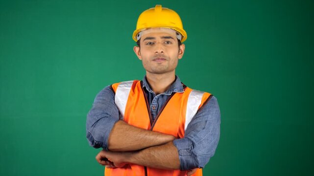 A worker wearing a yellow helmet posing for the camera. Green screen / Chroma shoot. Handsome young architect at the project site - construction worker  technical engineer  metro rail worker