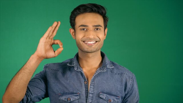 An attractive guy in his thirties showing the Ok super sign. Green screen / Chroma shoot. Cheerful young boy posing for the camera - modern lifestyle