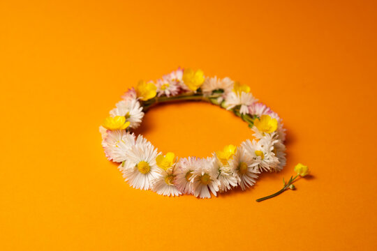 Midsummer wreath of wild flowers on orange background