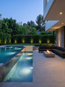 A modern house exterior with a pool and outdoor seating area at dusk.