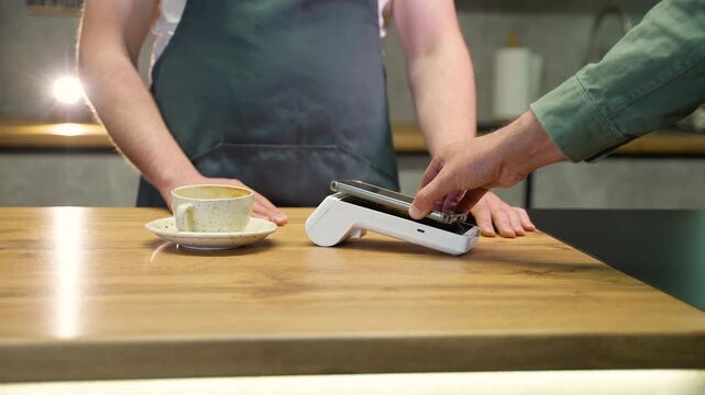 Customer using nfc smartphone payment at a coffee shop counter
