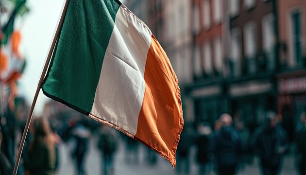 Green, white, orange flag waves in a blurred crowd on an urban street
