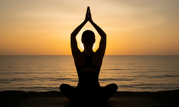 Silhouette of a woman practicing yoga meditation at sunset on a calm ocean beach
