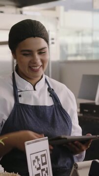 Vertical video: Approaching customer scanning QR while chef tapping tablet and handing box at cafe