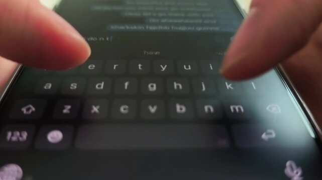Hands type on a smartphone keyboard in close up. Fingers tap and enter text while the mobile screen scrolls through messages. Digital texting and chat communication concept..