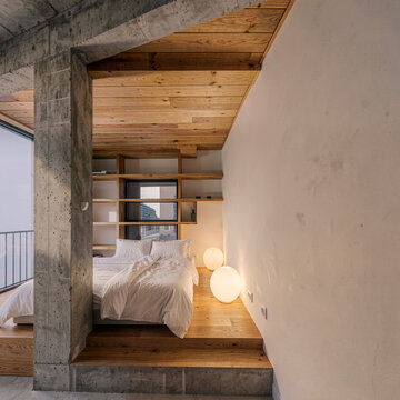 Modern minimalist bedroom with exposed concrete pillar, wooden ceiling, and spherical lamps.