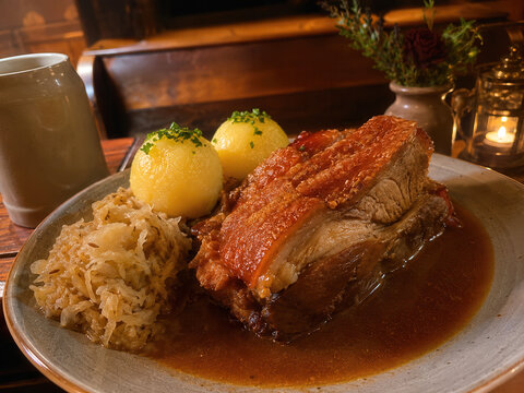 r&auml;nkisches Sch&auml;ufele bei Kerzenlicht
Rustikal angerichtetes fr&auml;nkisches Sch&auml;ufele mit Kl&ouml;&szlig;en, Sauerkraut und So&szlig;e in warmer traditioneller Atmosph&auml;re.