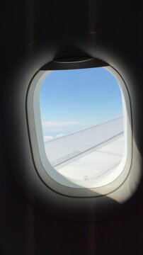 Airplane Window View: A serene view through an airplane window shows fluffy white clouds and a vast expanse of blue sky, with a wing visible beneath.