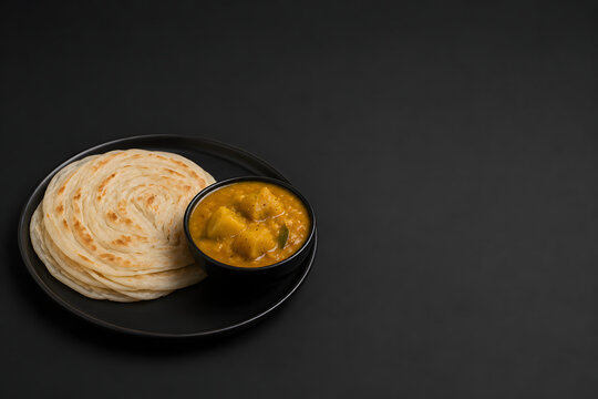 South Indian Tamil Nadu & Kerala parotta with potato kurma curry on black plate, top view with copy space