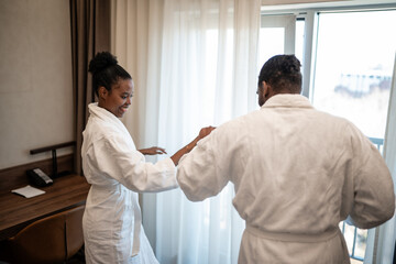 Obraz premium Happy couple dancing playfully in hotel room wearing bathrobes