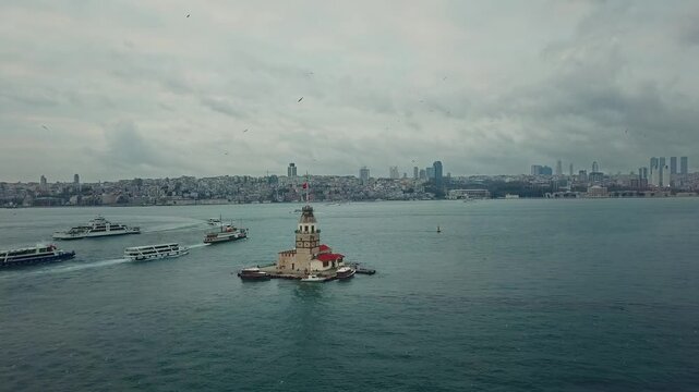 Maiden's Tower historic lighthouse surrounded by passenger ferry traffic in Bosphorus Strait against cloudy sky in Istanbul, Turkey