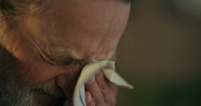 Thoughtful elderly bearded man in close-up looking down in warm light