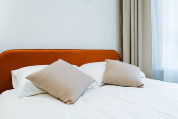 Obraz premium Minimal modern bed with rust-colored headboard and soft neutral pillows