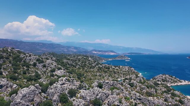 Rugged limestone terrain and turquoise anchorage bay with gulet boats near Kekova, Demre, Antalya, Mediterranean Turkey