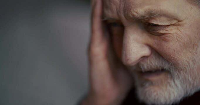 Thoughtful elderly man with gray beard in soft side profile light
