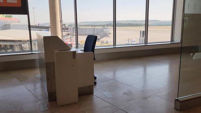 Modern airport terminal gate with empty boarding desk and runway view