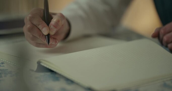 Close-up of hand writing notes in an open notebook