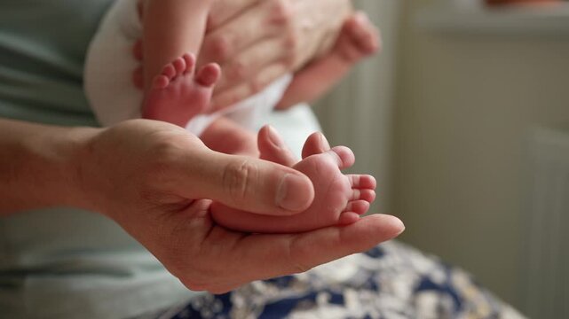 Close up view of a caring father's hands tenderly holding the small, delicate feet of his newborn baby boy, symbolizing love, protection, family connection, and the joy of new life