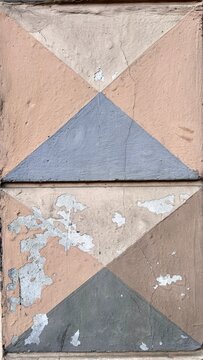 geometric triangle pattern in beige, cream, and gray on weathered concrete wall with copy space