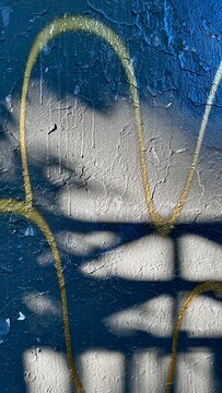 peeling grey paint with yellow graffiti lines and quaint shadows on textured wall with copy space