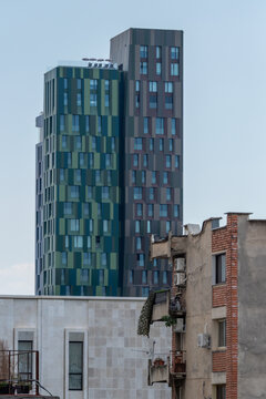 View of a modern skyscraper with a pixelated green and brown facade standing behind older residential buildings in Tirane, Tirana County, Albania.