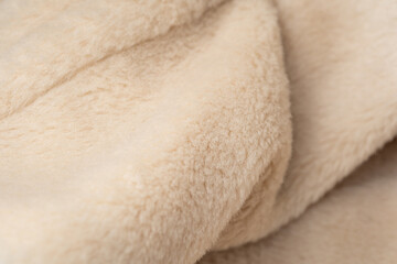 Detailed macro view of luxurious warm cream colored fluffy soft plush fabric textile background © reddish